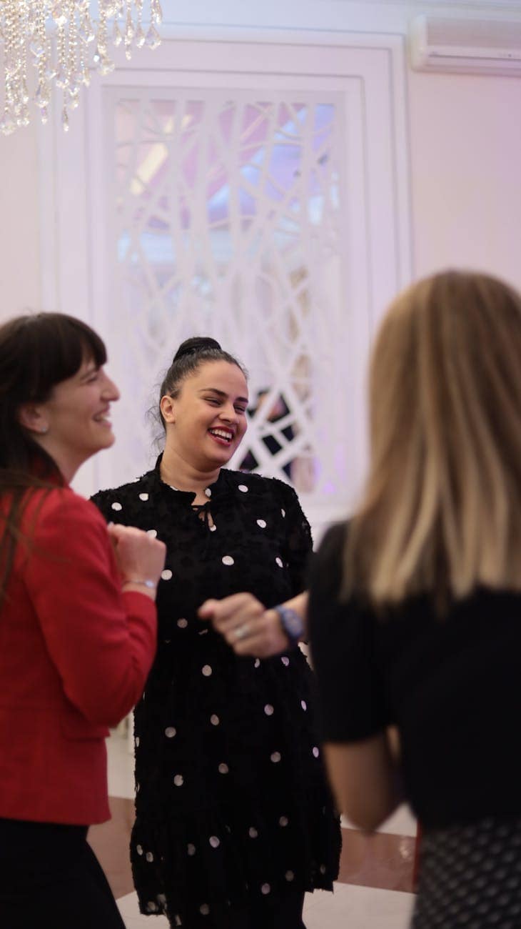women smiling near a white wall